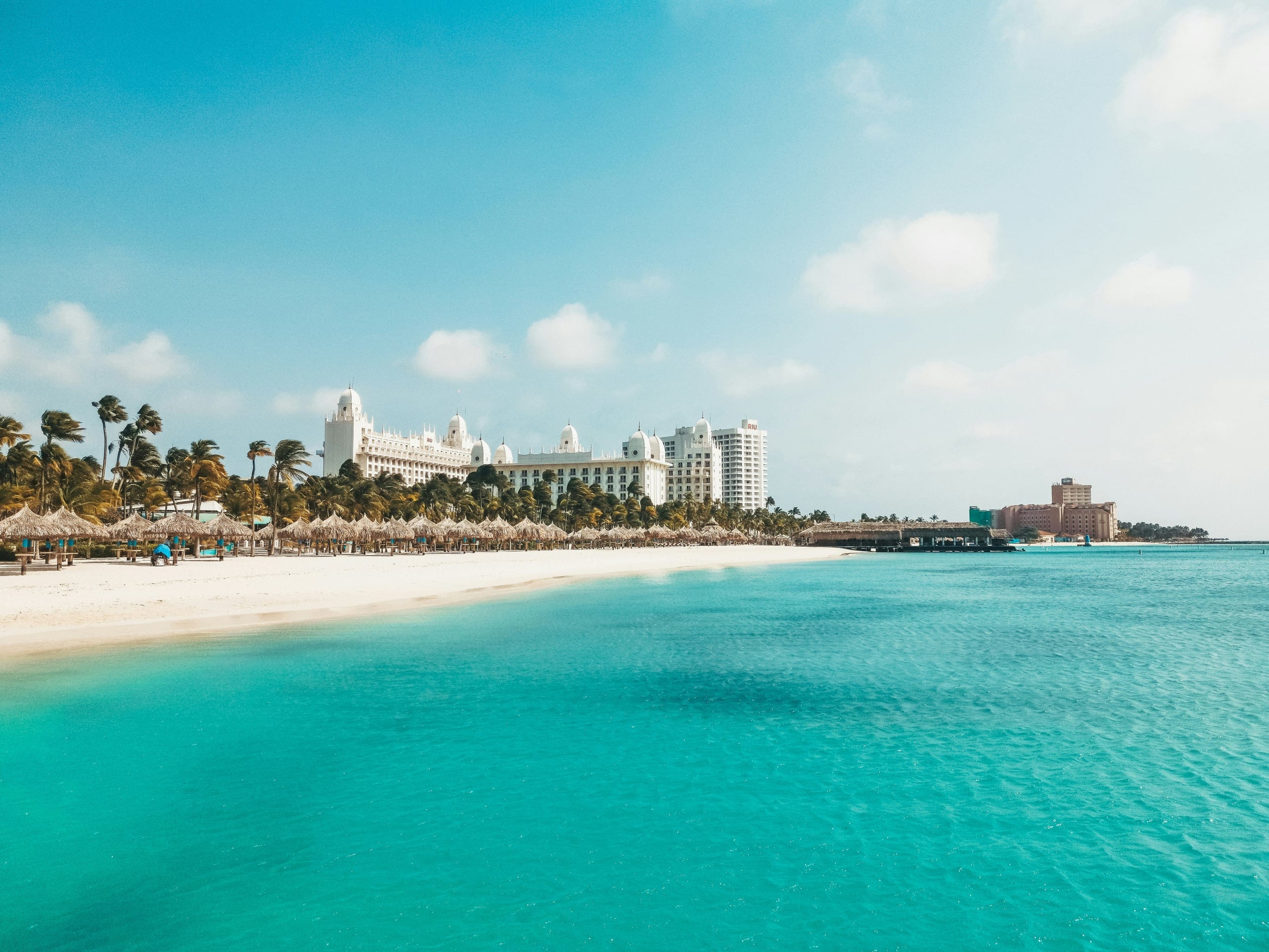 The white domes of the Riu Palace and the high-rise hotels behind Palm Beach, Aruba, seen from turquoise water
