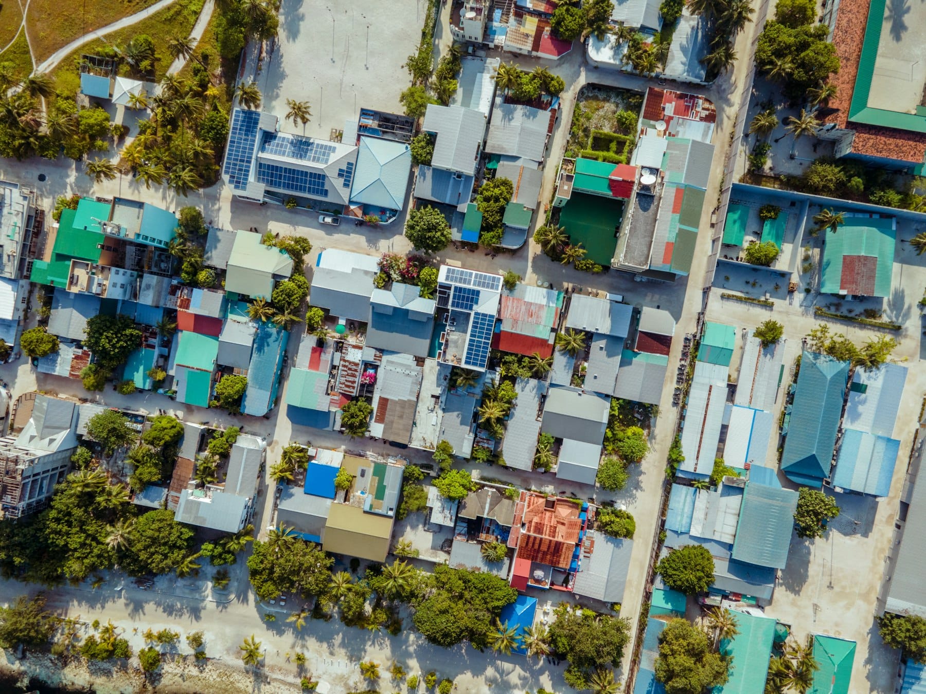 Maafushi seen from directly above, colored roofs and small yards packed tight along sandy streets