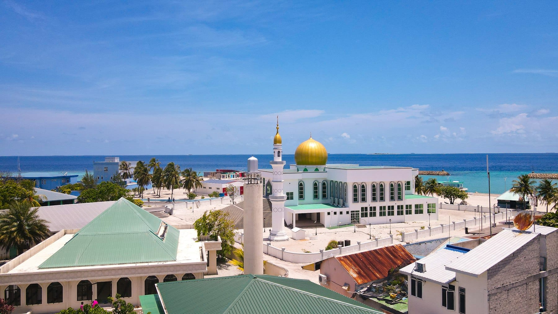 The gold-domed mosque on Ungoofaaru standing above the rooftops with the sea behind it